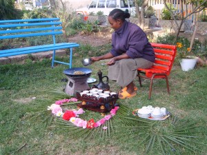 Una donna arrostisce i chicchi di caffè durante la cerimonia, sempre arricchita di foglie e fiori